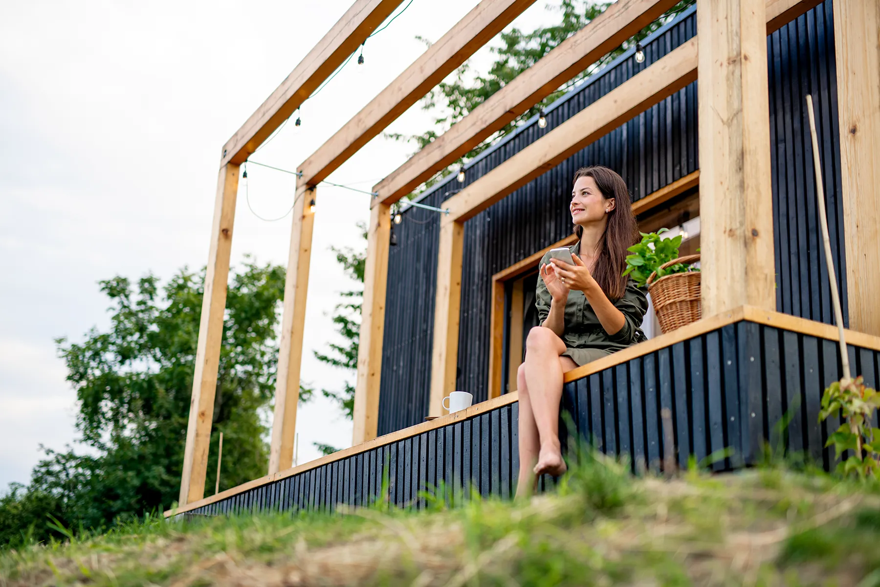 Young Woman With Smartphone Outdoors, Weekend Away In Container House In Countryside. Young Woman With Smartphone Outdoors, Weekend Away In Container House In Countryside.