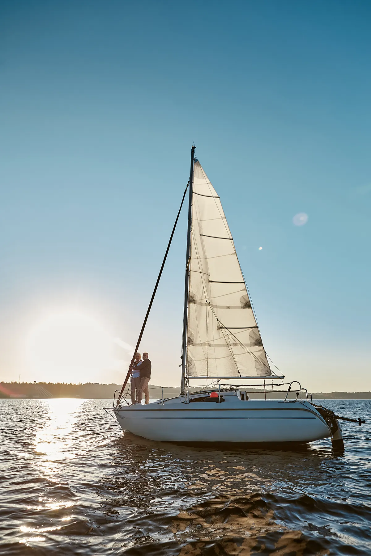 Romantic senior couple enjoying amazing sunset while standing on the side of sail boat Romantic senior couple enjoying amazing sunset while standing on the side of sail boat