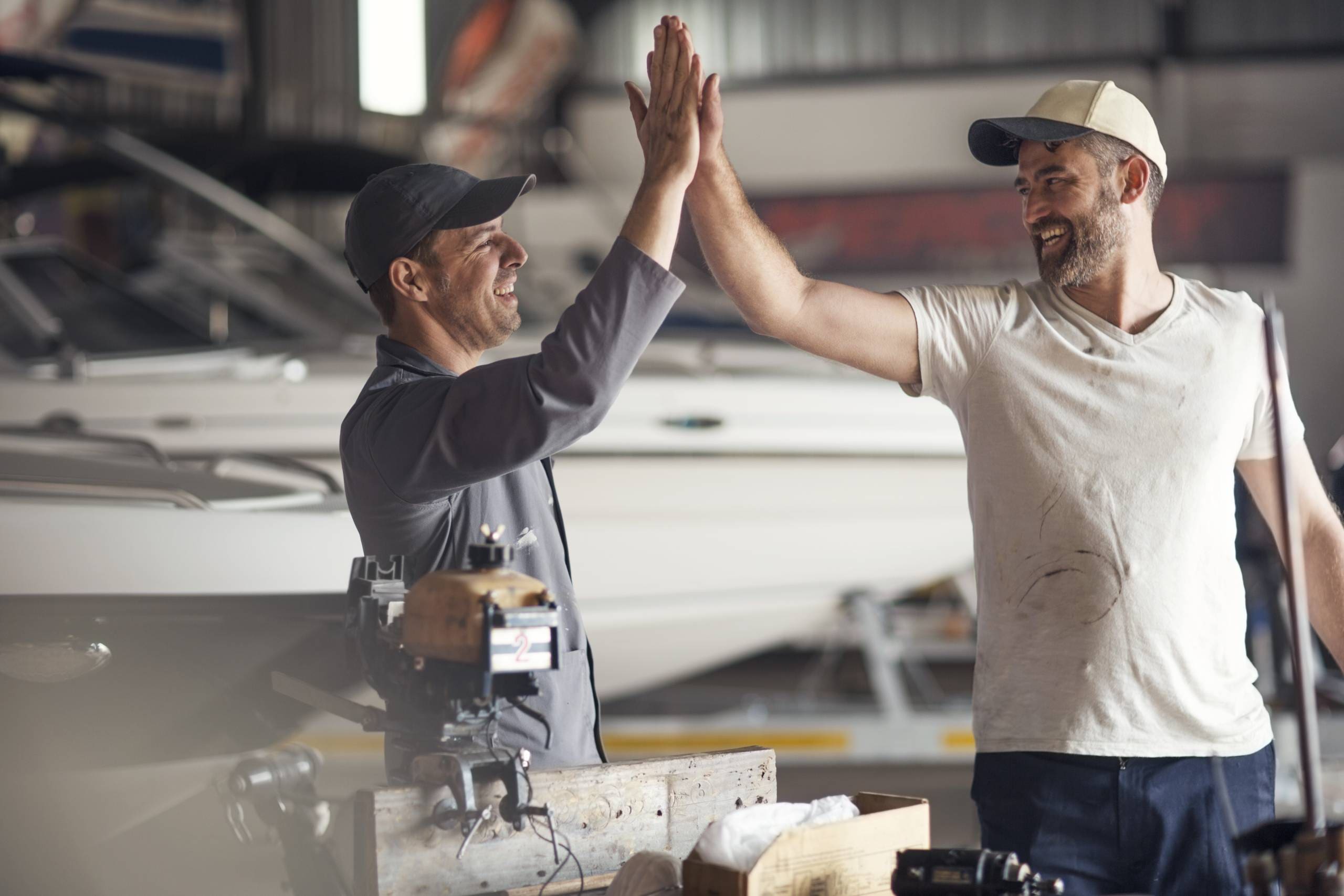 Two men celebrating a successful watermaker installation on yacht.